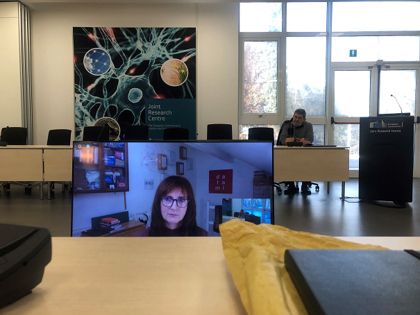 Jill Townsley on a screen presenting in a conference room at JRC 