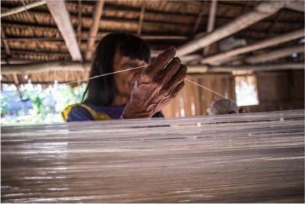 Artist weaving threads together at the loom